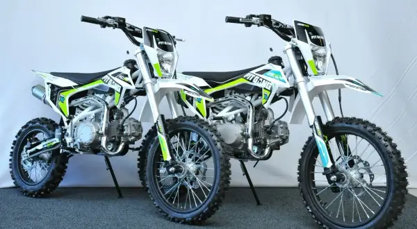 Dwa biało-zielone motocykle typu pit bike stojące obok siebie.