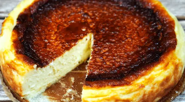 En krämig baskisk cheesecake med en härligt bränd yta, en bit är bortskuren.