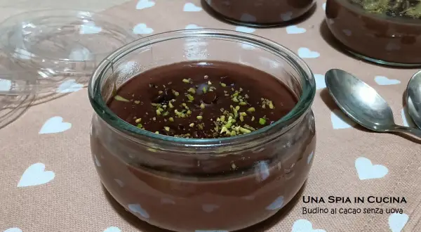 Budino al cioccolato fatto in casa, guarnito con pistacchi tritati, servito in vasetti di vetro su un tovagliolo con cuoricini.