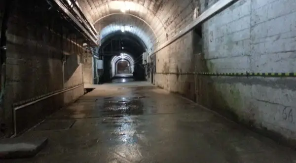 Wnętrze tunelu zapory Solina. Zwiedzanie cennik. Wilgotna posadzka, betonowe ściany, łukowe sklepienie z instalacjami.
