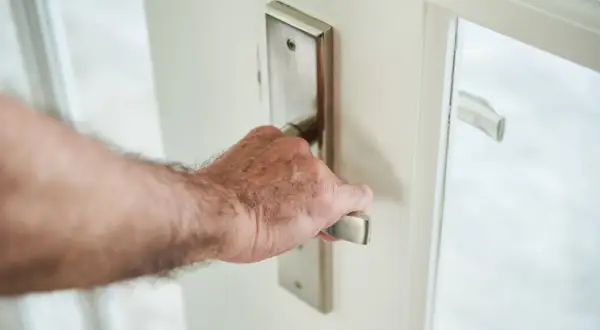 Main d'homme ouvrant une porte blanche, le bruit de la porte qui grince se fait entendre.
