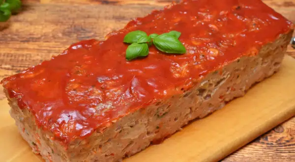 Pieczeń rzymska z sosem pomidorowym i bazylią na desce.