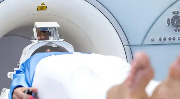 Pacjent leży w aparacie do rezonansu magnetycznego. Przed badaniem warto dowiedzieć się, czy do tomografii trzeba zdjąć kolczyki.