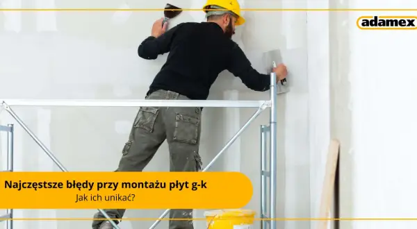 Pracownik na rusztowaniu wykonuje prace wykończeniowe przy ścianie z płyt g-k. Sucha zabudowa wymaga precyzji.