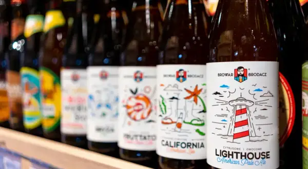 Rząd butelek piwa z etykietami Browar Brodacz. Na pierwszej widocznej etykiecie stylizowana latarnia morska i napis "Lighthouse".