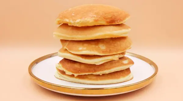 Stos puszystych, złotych pancake'ów na talerzu. Idealny przepis na śniadanie.