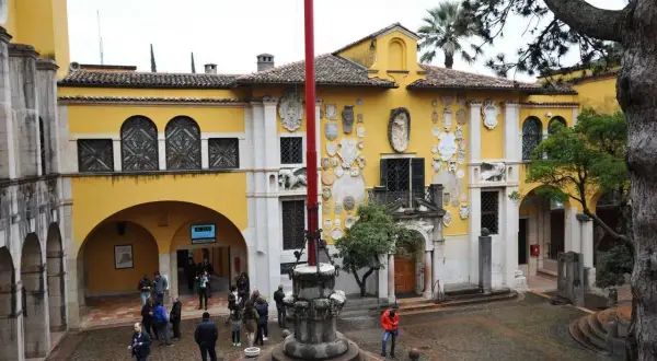 Cortile del Vittoriale degli Italiani, con la facciata gialla decorata da stemmi e sculture. Un luogo affascinante da visitare.