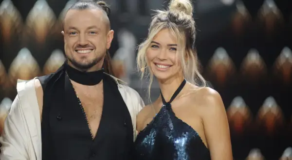 Sandra Kubicka i Baron uśmiechają się do obiektywu. Ona w błyszczącej sukience, on w nietypowej stylizacji.