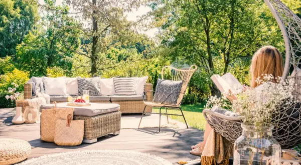 Relaks na tarasie w stylu boho: rattanowe meble, plecione kosze i okrągły dywan tworzą przytulną przestrzeń. Inspiracje dla Twojego ogrodu.