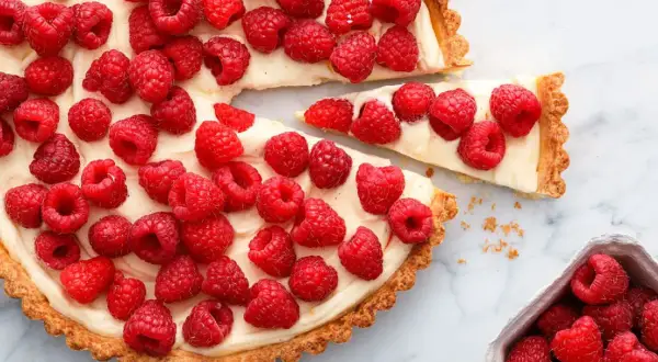 Tarta z malinami i mascarpone, ozdobiona białą czekoladą, kusi świeżością i kremowym nadzieniem.