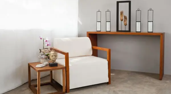 Kreative Ideen für eine tote Ecke im Wohnzimmer: Sessel, Beistelltisch mit Buddha-Kopf und Orchidee, Konsolentisch mit Kerzenhaltern und Händen-Deko.