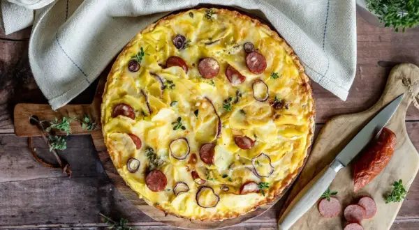 Herzhafte Kartoffeltorte mit Speck und Zwiebeln, goldbraun gebacken und mit frischen Kräutern garniert. Ein Genuss für jeden Anlass.