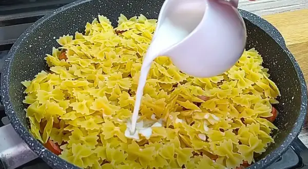 Makaron farfalle z kiełbasą w sosie śmietanowym, gotowany na patelni.