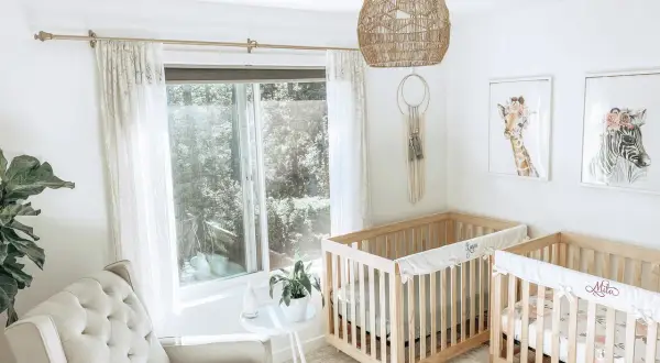 A serene twin m nursery with two wooden cribs, a plush armchair, and whimsical animal art.