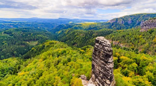 Piękne czeskie góry, gdzie jechać? Malowniczy krajobraz z dominującą skalną iglicą i bujnymi lasami.