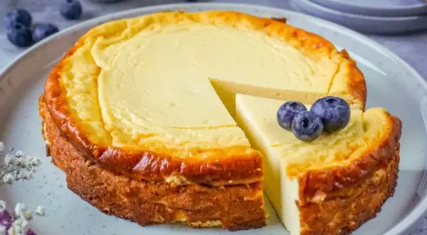 Ein saftiger Quarkkuchen ohne Boden, goldbraun gebacken und mit frischen Blaubeeren garniert. Ein Genuss für jeden Kaffeetisch!