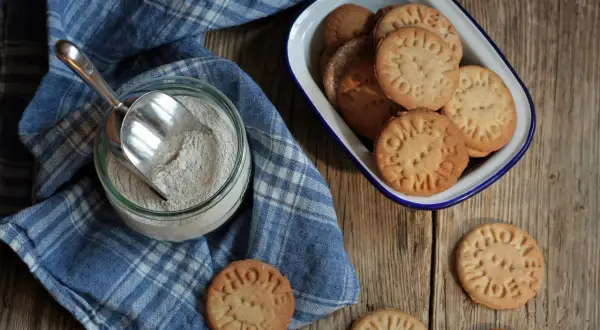 Domowe ciastka z mąki gryczanej, z napisem "HOME MADE", obok słoika z mąką i miarką.