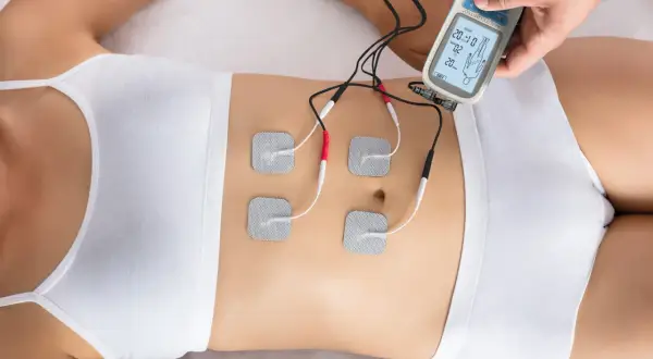 Elektrostymulacja mięśni brzucha za pomocą urządzenia z elektrodami.