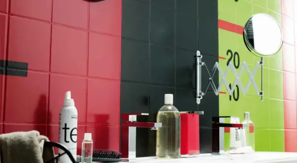 Un mur de salle de bain aux carreaux rouges, noirs et verts, avec des marques de croissance. Une inspiration peinture céramique pour un décor audacieux.