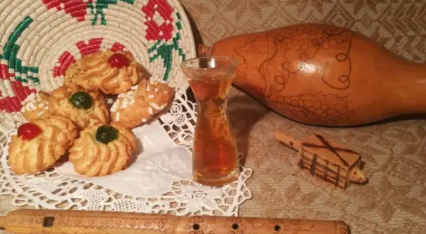 Biscotti decorati, un bicchierino di vernaccia di Oristano, una zucca intagliata e un flauto in legno.