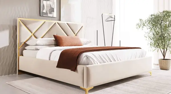 Elegancka, biała sypialnia glamour z łóżkiem tapicerowanym beżową tkaniną i złotymi detalami. Miękkie poduszki i narzuta tworzą przytulną atmosferę.