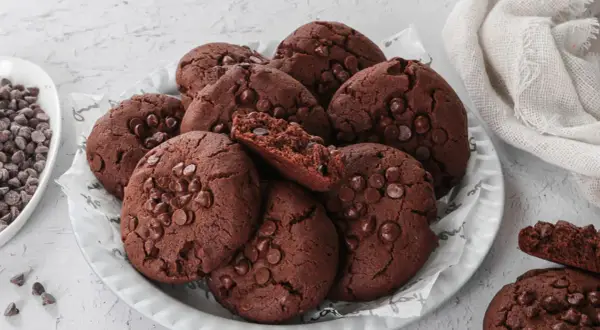Un mucchio di deliziosi biscotti al cioccolato, perfetti per chi cerca biscotti senza burro. Alcuni sono interi, altri spezzati, rivelando un interno morbido e ricco.