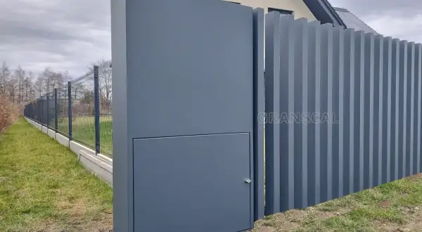 Nowoczesne ogrodzenie z pionowych paneli i słupka z ukrytą skrzynką elektryczną. Czy skrzynka elektryczna musi być w ogrodzeniu? Tutaj jest dyskretnie wkomponowana.