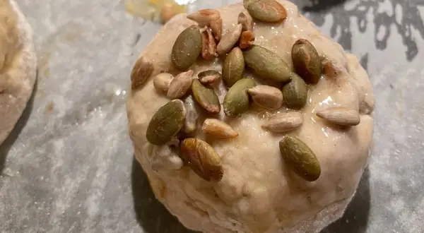 Nybakade glutenfria frallor med pumpa- och solrosfrön på en bakplåt.