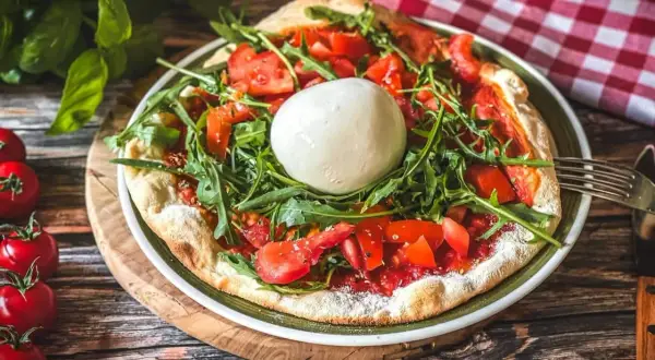 Pizza mit frischen Tomaten, Rucola und einer Kugel Burrata, die Lust auf burrata selber machen macht.