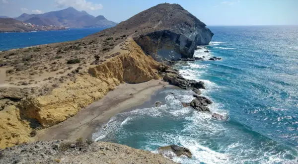 Paisaje de la cala amarilla en Almería, con acantilados dorados, arena y mar azul turquesa.
