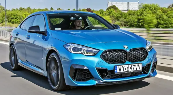 Niebieskie BMW 2 Gran Coupe pędzi autostradą. Kierowca skupiony na drodze.