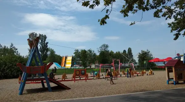 Plac zabaw z atrakcjami dla dzieci nad Balatonem: zjeżdżalnie, huśtawki i domek.