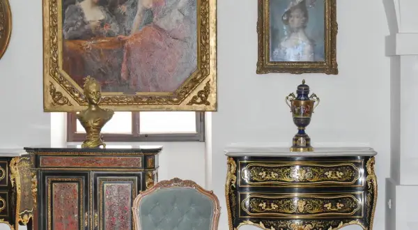 Antiquariato di lusso: un busto dorato su un mobile intarsiato, un vaso decorato e dipinti d'epoca. Un'ispirazione per chi vuole diventare antiquario.