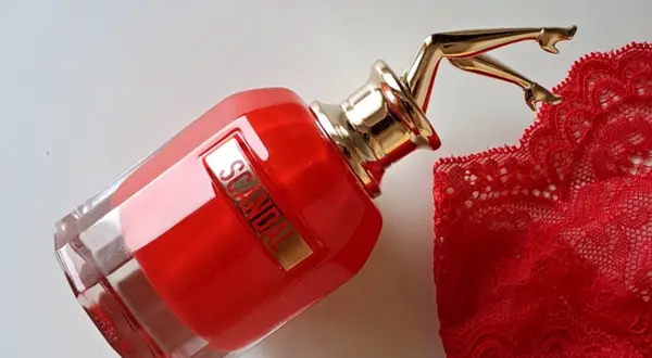 Czerwony flakon perfum Scandal EDP z złotymi nogami i koronkową bielizną. Zapach budzi skojarzenia z odwagą i zmysłowością.