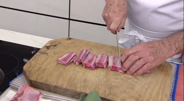 Chef corta costillas de cerdo en trozos para una deliciosa terrina de costilla.