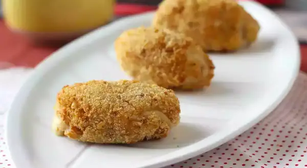 Trois croquetas espagnoles dorées et croustillantes sur une assiette blanche.