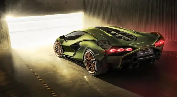 Zielony Lamborghini Sian z miedzianymi felgami, wychodzący z garażu w blasku słońca.