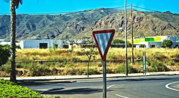Señal de ceder el paso en una carretera con montañas al fondo.