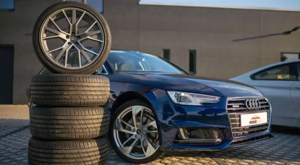Mörkblå Audi A4 B9 med en stapel däck och en fälg.