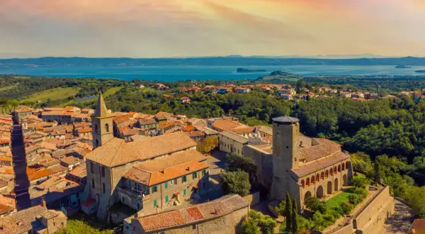 Panoramica di un borgo italiano con un lago sullo sfondo. Scopri cosa vedere a Valentano: un incantevole paesaggio tra storia e natura.