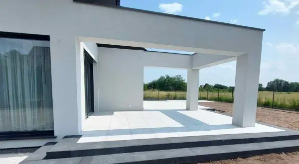 Nowe schody i taras z białej kostki betonowej przy nowoczesnym domu.