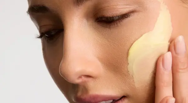 Application d'une crème riche en céramides pour une peau éclatante. Les doigts doux étalent la texture onctueuse.