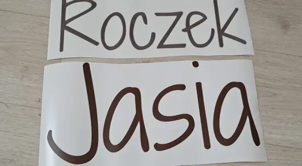 Napis "Roczek Jasia" na białych arkuszach, gotowy do dekoracji przyjęcia.