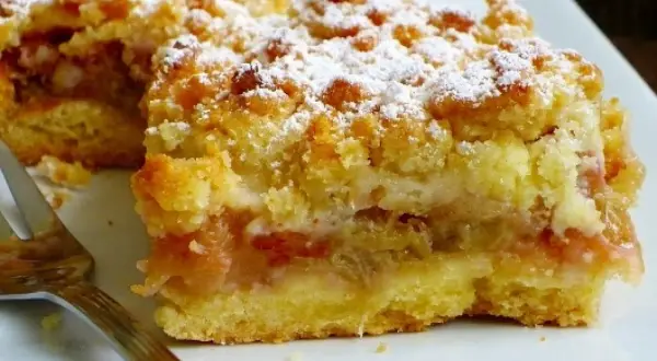 Kruche ciasto z rabarbarem i kruszonką, posypane cukrem pudrem. Idealne na letnie popołudnie.