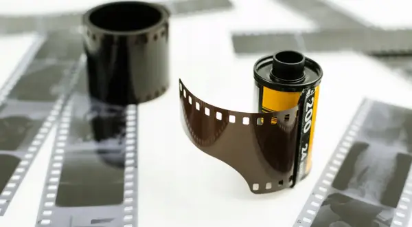 Rolka filmu z wyciągniętym fragmentem i negatywy. Jak z filmu zrobić zdjęcie? To pytanie wraca wraz z modą na analog.