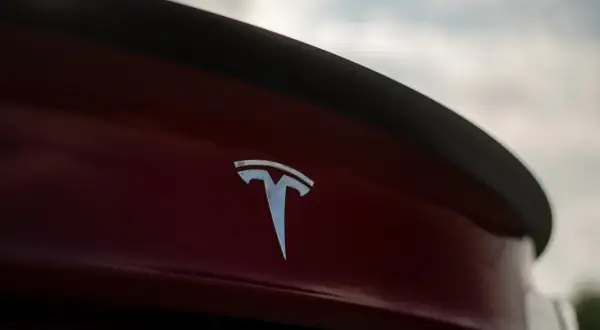 Chromowane logo Tesli na czerwonym samochodzie. Tesla, choć założona w USA, ma korzenie w Serbii, kraju wynalazcy Nikoli Tesli.