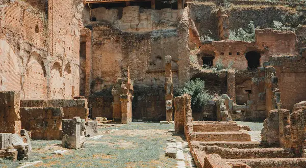 Rovine antiche nel foro romano palatino, con mattoni rossi e vegetazione che cresce tra le pietre.