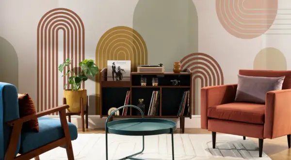 Salotto con poltrone colorate, mobile bar con giradischi e vinili, tavolino verde acqua e decorazioni murali in stile mid century.