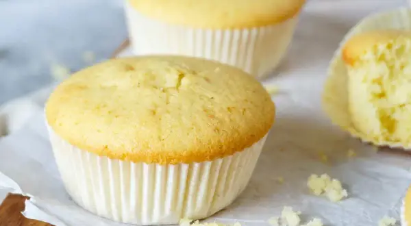 Zarte Muffins, perfekt für das Muffins Grundrezept. Einer ist angeschnitten und zeigt die fluffige Textur.