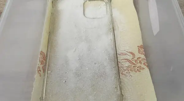 Przezroczyste etui na telefon zasypane sodą oczyszczoną, przygotowane do czyszczenia. To prosty sposób, jak wyczyścić zżółknięte etui.